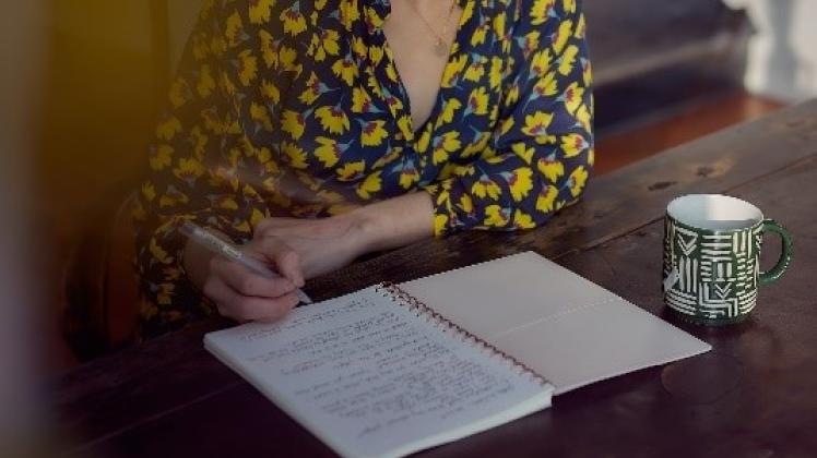 Kvinde sidder tænksom med papir og pen